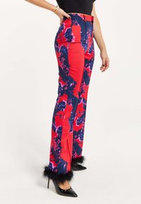 Red and navy floral-patterned pants with a high waist, wide legs, and black faux fur accents at the hem. Paired with black heels.