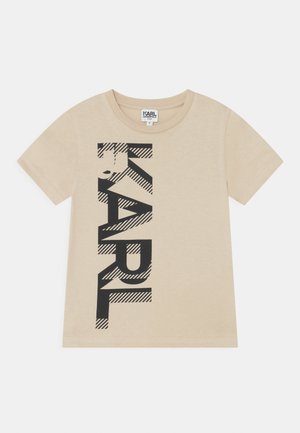 Beżowy dziecięcy t-shirt z krótkim rękawem z pionowym czarnym napisem "KARL" i wzorem w paski na jednolitym tle.