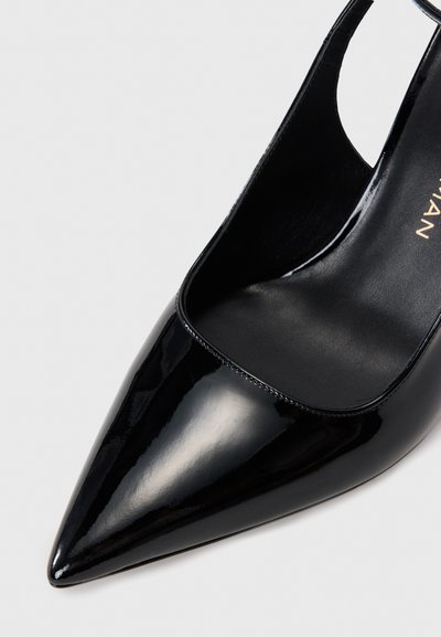 Black patent leather high heel shoe with a pointed toe, open sides, and a smooth texture. Minimalist design with no embellishments.