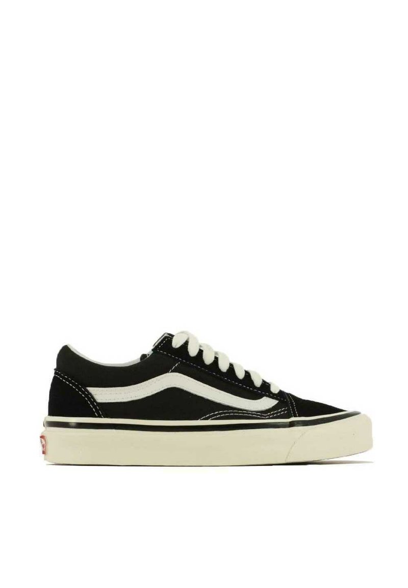 Sneaker nera in tela a basso profilo con lacci bianchi e una distintiva striscia bianca laterale. Presenta cuciture a contrasto e una suola in gomma crema.
