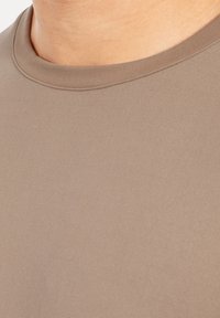 Beige T-Shirt mit kurzen Ärmeln und rundem Ausschnitt. Glatte Textur und enganliegendes Design, das auf Einfachheit und Komfort fokussiert ist.