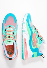 Nike Air-sneakers har ett ovandel i mesh i turkos och grön, med korallfärgade accenter och en synlig luftkuddsenhet i hälen.