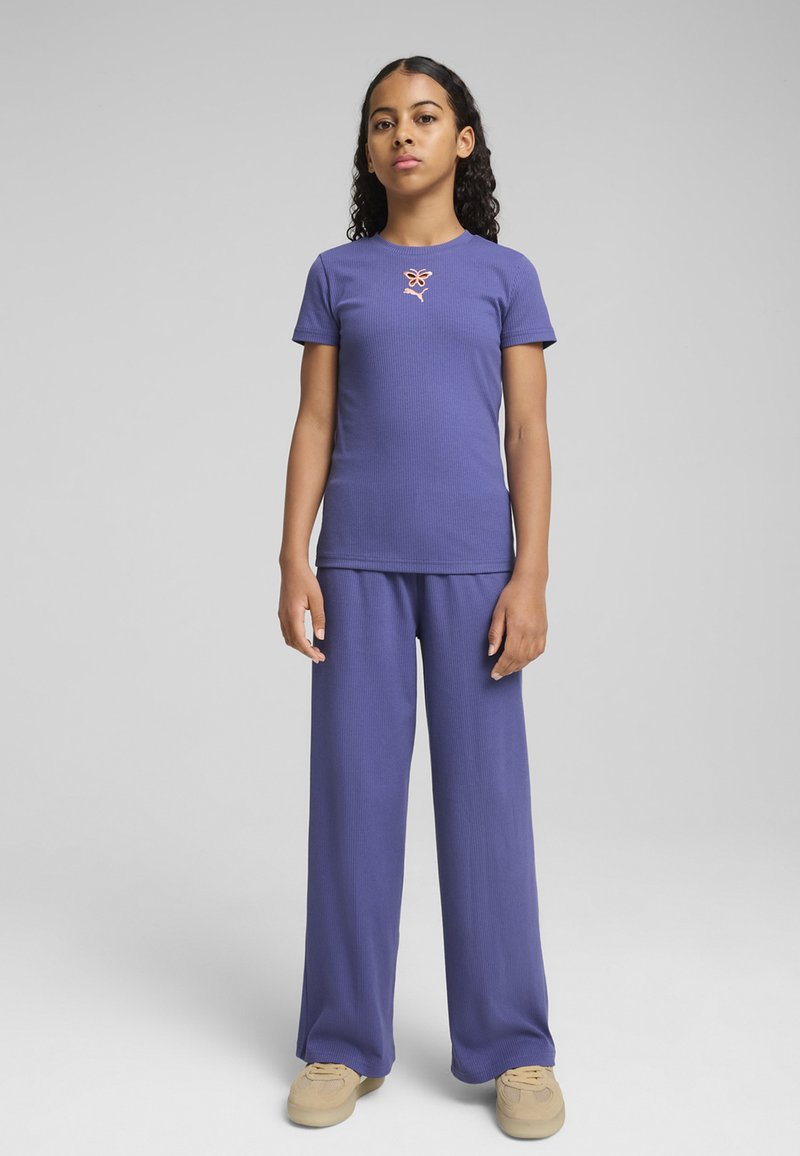 T-shirt violet à rayures, à manches courtes, avec un petit logo brodé orange, associé à un pantalon violet ample assorti.