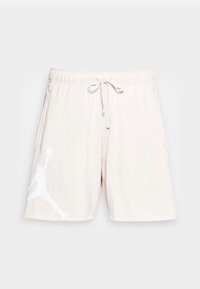 Shorts sportivi beige chiaro realizzati in materiale morbido, con vita elastica e cordoncino di regolazione, e un grafico con logo bianco sulla gamba sinistra.