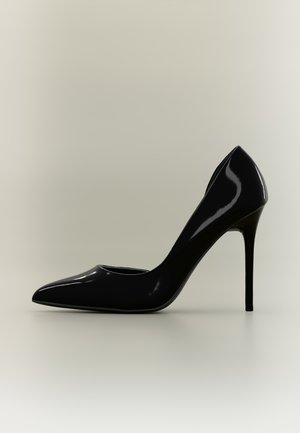 Escarpin en cuir verni noir à talon haut avec bout pointu et talon aiguille fin sur un fond clair uni.