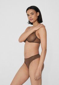 Bra und passende Unterhose aus glattem, transparentem Material in Braun. Der Bra hat eine geformte Passform; die Unterhose hat einen einfachen Schnitt und einen Bund.