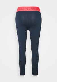 Leggings blu navy con una ampia vita rosa che presenta il logo "PUMA". Il materiale è morbido e elasticizzato, progettato per garantire comfort e mobilità.