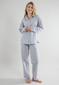 Set di pigiama a righe blu e bianche con camicia a bottoni dotata di taschino e pantaloni abbinati con orli. Realizzato in tessuto morbido.