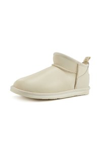 Botas de tobillo de cuero beige con punta redondeada, un puño doblado y una suela texturizada. Incluyen una pestaña para facilitar el uso.