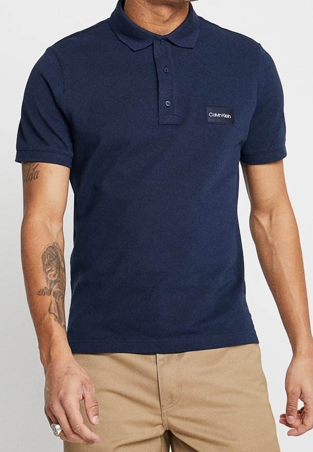 Polo bleu marine en coton, doté d'un col à trois boutons, de manches courtes et d'une patch logo Calvin Klein sur la poitrine.