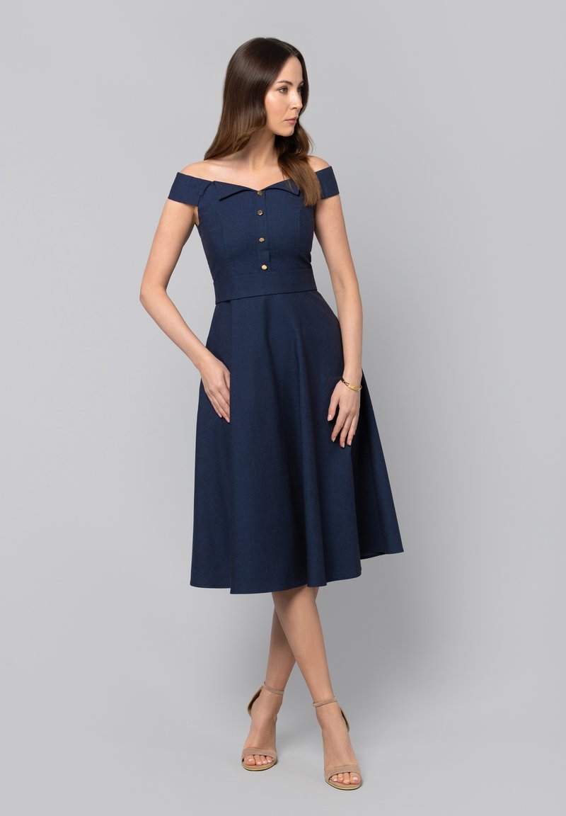 Granatowa sukienka bez ramiączek z dopasowanym gorsetem, detalami w postaci guzików i rozkloszowanym dołem. Wykonana z teksturowanej tkaniny. Regulowane ramiączka.