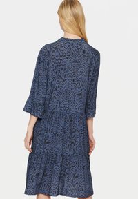 Vestito blu con motivi a disegni, maniche a tre quarti, orlo arricciato e design a balze, caratterizzato da una stampa astratta in toni di blu scuro e chiaro.