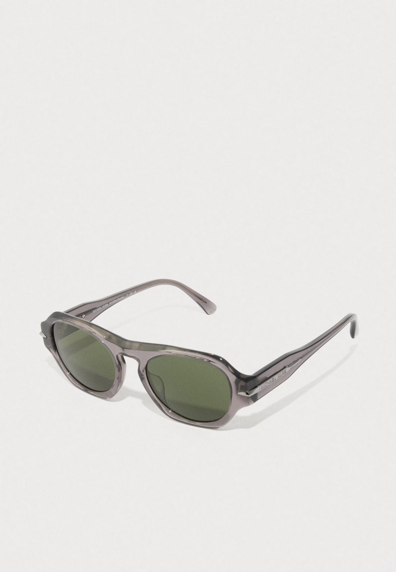 Ochelari de soare gri translucizi cu lentile verzi, formă rotundă și brațe elegante cu detalii gravate ale brandului.