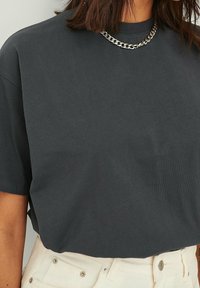 T-shirt corto grigio scuro in cotone morbido, con scollatura a girocollo e una collana in argento come accessorio.
