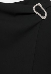 Fekete, sima textúrájú anyag, fényes ezüst ovális csattal, melyet strasszok díszítenek.