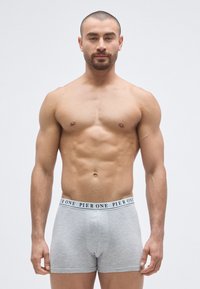 Γκρι βαμβακερά ανδρικά μπόξερ με μαύρη ζώνη μέσης με την ετικέτα "PIER ONE", εφαρμοστή σχεδίαση, ομαλή υφή και μήκος μέχρι το μέσο του μηρού.