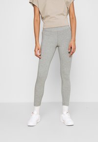 Gray leggings made of stretchy material, featuring a fitted design and a smooth texture. Paired with a light brown top and white sneakers.