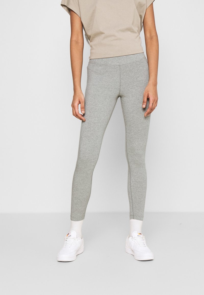 Gray leggings made of stretchy material, featuring a fitted design and a smooth texture. Paired with a light brown top and white sneakers.