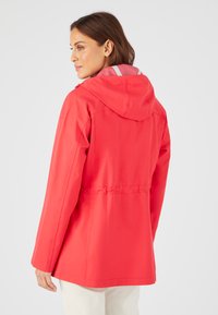 Giacca impermeabile rossa con cappuccio, vita svasata e colletto interno a contrasto. Texture liscia e maniche lunghe.