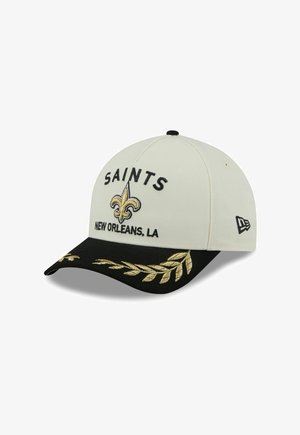 Die Kappe hat einen weißen Stoffkörper mit einem schwarzen Schirm. Auf der Vorderseite sind "SAINTS" und ein goldenes Fleur-de-lis-Logo gestickt. Goldene Blattschmuckakzente.