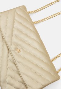 Zlatá prošívaná kožená kabelka s diagonálním vzorem a zlatým řetízkovým popruhem. Obsahuje malý, vytlačený detail loga.
