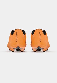 Scarpe da calcio arancioni con tomaia testurizzata, dettagli neri e cinque tacchetti su ciascuna suola per una migliore trazione. Logo del marchio "ULTRA" visibile sul tallone.