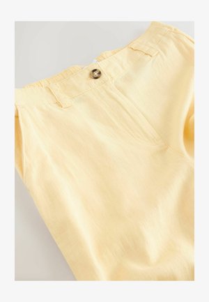 Šviesiai geltonos kelnės iš minkštos medžiagos, turinčios priekinį užsegimą su sagomis, siaurėjantį siluetą ir minimalistinį dizainą su subtilia tekstūra.