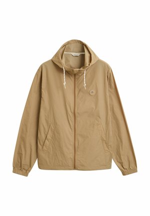 Lätt tanfärgad jacka med huva, dragkedjestängning, elastiska ärmslut och sidofickor. Har en liten rund logotyp på vänster bröstområde.