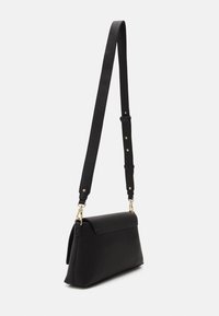 Černá kožená taška přes rameno s texturovaným povrchem, obdélníkovým tvarem, nastavitelným popruhem, zlatými kovovými doplňky a klopovým uzavřením.