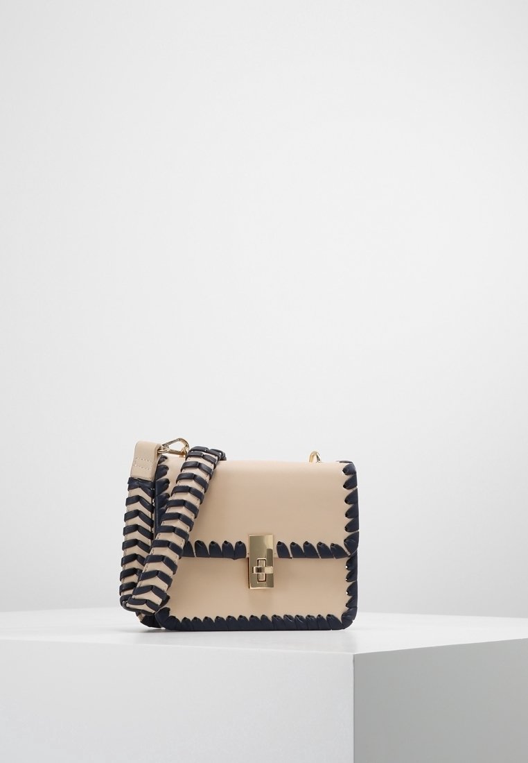 Borsa a mano in pelle beige con bordo ondulato blu navy, chiusura dorata e tracolla intrecciata. Forma rettangolare strutturata con una superficie liscia.