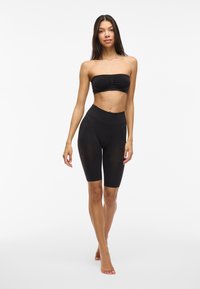 Top noir sans bretelles avec un détail froncé à l'avant et short de vélo noir taille haute. Tissu lisse et extensible avec une silhouette ajustée.