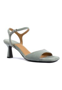 Samtgrüne High-Heel-Sandalette mit offener Zehe und Knöchelriemen, ausgestattet mit einem verjüngten schwarzen Absatz und beigem Innenfutter.