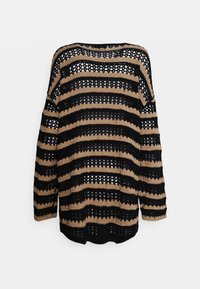 Sweter na szydełku z naprzemiennymi czarnymi i beżowymi paskami, o otwartej, ażurowej fakturze, szerokim dekolcie w łódkę oraz długich rękawach z opuszczonymi ramionami.