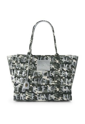 Sac fourre-tout à motif camouflage en tons noirs, blancs et gris, avec un texte style graffiti et un patch rectangulaire argenté sur le devant.