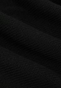 Črno pleteno blago z teksturirano površino, ki vsebuje enakomeren vzorec prepletenih niti, ustvarja mehko, prožno drapiranje.