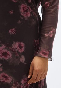 Rochie cu mâneci lungi, cu fundal negru și model floral în nuanțe de roz și burgund, confecționată dintr-un material ușor, transparent.