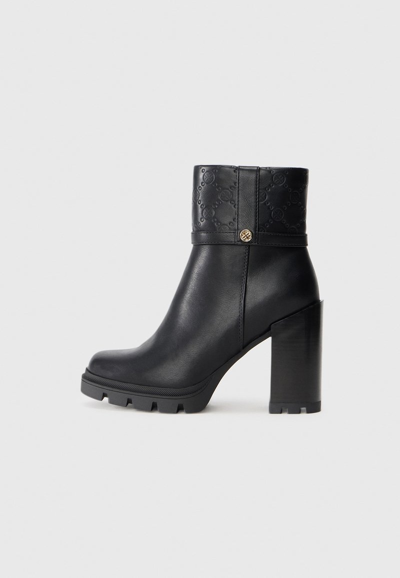 Bottine en cuir noir avec talon carré épais, parement texturé comportant un motif en relief, et petit bouton doré sur le côté.