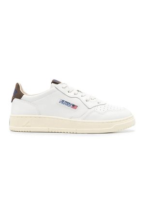 Sneaker bianca low-top con punta traforata, suola crema, tallone marrone e patch blu con logo e bandiera americana sul lato.