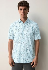 Camicia a maniche corte in tessuto azzurro chiaro con un motivo floreale in tonalità più scure, dotata di colletto button-down e orlo dritto.