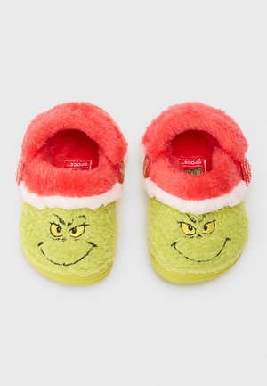 Grønne, fluffy slippers med design af Grinch-ansigt, med blødt rødt foret og hvid kant. Slip-on stil med tekstureret sål.