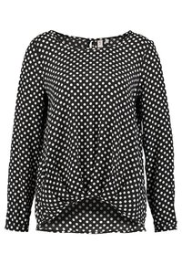 Blouse noire à manches longues avec pois blancs et un détail torsadé froncé à l'ourlet avant.