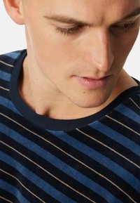 Suéter a rayas azul y marino con un cuello de canalé, que presenta rayas horizontales de diferentes anchos y una textura suave.