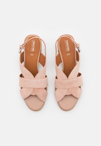 Paire de sandales ouvertes en daim beige avec des brides croisées et des boucles ajustables à la cheville, semelles plates et semelles intérieures de marque.