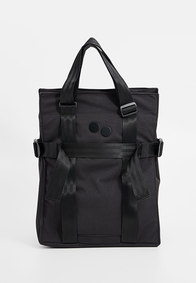 Black fabric tote bag with dual top handles, adjustable straps, and two circular rivets on the front. Sturdy, textured surface.