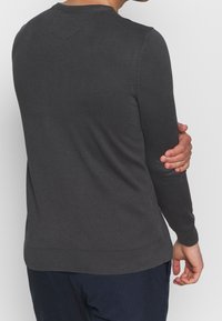 Dunkelgrauer Langarmpullover mit gerippter Textur und Rundhalsausschnitt, der eine enganliegende Passform und kontrastierende Saumdetails aufweist.