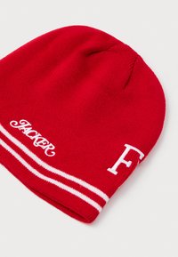 Gorro de punto rojo con franjas blancas, que presenta texto blanco bordado en la parte frontal que dice "HACKER" y una letra "F" destacada.
