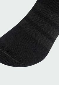 Calcetín negro de tobillo con un diseño texturizado y acanalado, que presenta una sección con un patrón sutil. El material parece suave y elástico, garantizando comodidad.