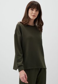 Felpa verde oliva con maniche lunghe, scollatura rotonda e vestibilità comoda. Tessuto morbido con polsini a coste e orlo largo.