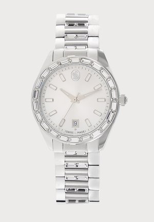 Montre-bracelet en métal argenté avec cadran blanc, index rectangulaires, affichage de la date à 6 heures et bracelet à maillons métalliques.