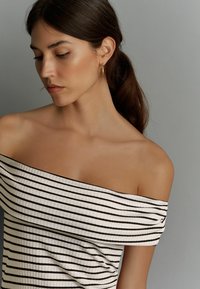 Off-the-shoulder ribbed top met zwart-witte horizontale strepen; heeft een aansluitend ontwerp en subtiele draping bij de halslijn.